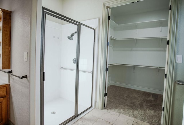 bathroom with a spacious closet, a shower stall, and vanity