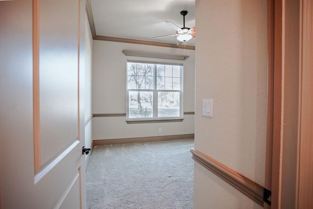 empty room featuring light carpet, baseboards, a ceiling fan, and crown molding