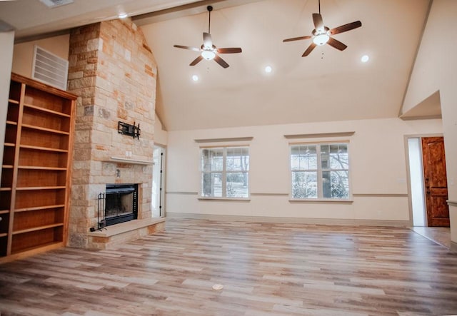 unfurnished living room featuring baseboards, a stone fireplace, and light wood finished floors