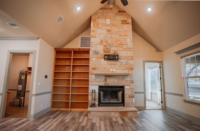 unfurnished living room featuring electric water heater, a stone fireplace, wood finished floors, and visible vents