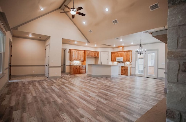 unfurnished living room with light wood-type flooring, high vaulted ceiling, and visible vents