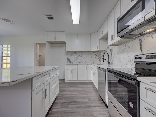 kitchen with decorative backsplash, stainless steel appliances, sink, white cabinets, and light hardwood / wood-style floors