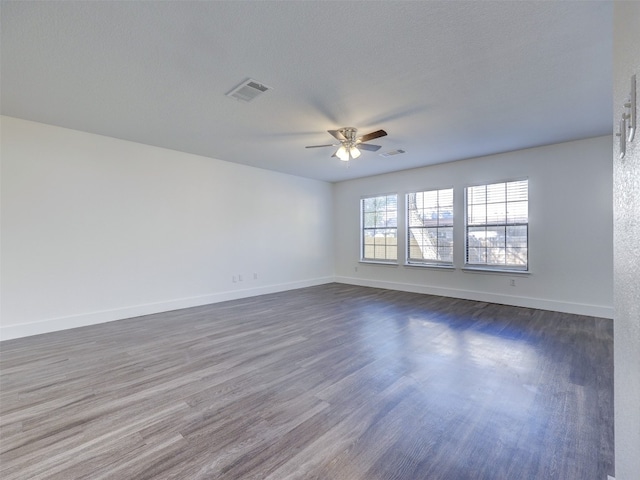 empty room with ceiling fan, dark hardwood / wood-style flooring, and a textured ceiling