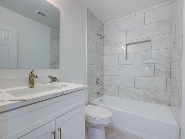 full bathroom featuring vanity, tiled shower / bath combo, and toilet