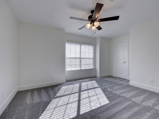 spare room featuring dark carpet and ceiling fan