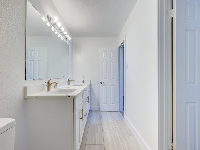 bathroom featuring a textured ceiling, vanity, and toilet