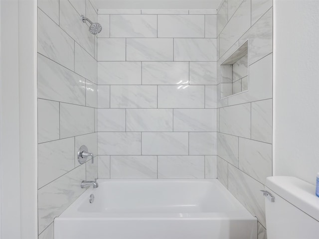 bathroom featuring toilet and tiled shower / bath