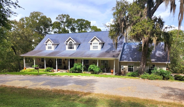 cape cod-style house featuring a front lawn and covered porch