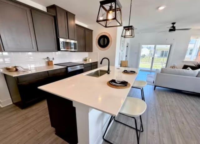 2026 Cora Ivy Ln, Round Rock, TX 78665 - kitchen with wood finished floors, a sink, decorative backsplash, open floor plan, and stainless steel microwave