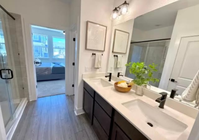 2026 Cora Ivy Ln, Round Rock, TX 78665 - bathroom featuring wood finished floors, a sink, double vanity, and a stall shower