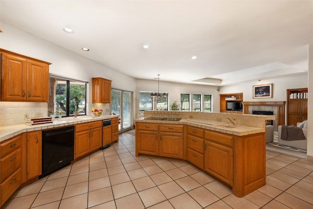 kitchen with tasteful backsplash, sink, black appliances, light tile patterned floors, and decorative light fixtures