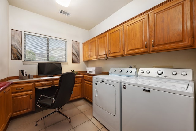 clothes washing area with washer and dryer, cabinets, and light tile patterned flooring