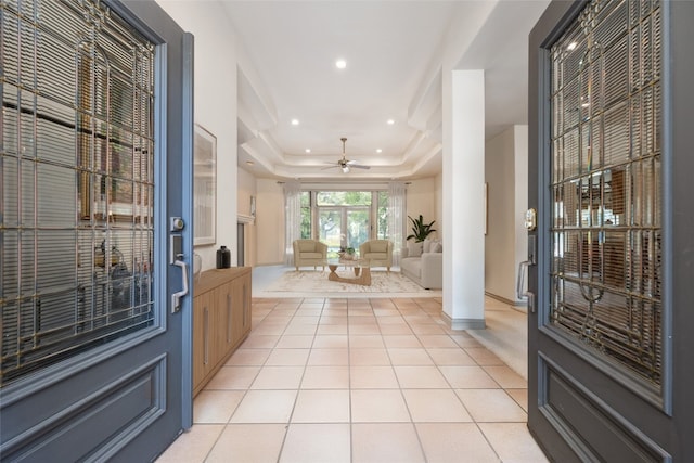 tiled entrance foyer with ceiling fan and a tray ceiling