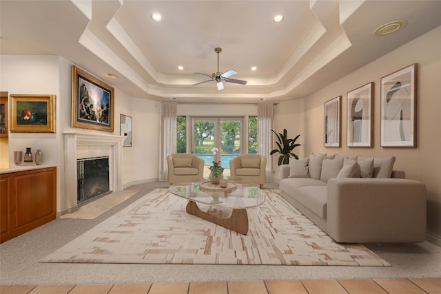 tiled living room with a tray ceiling and ceiling fan