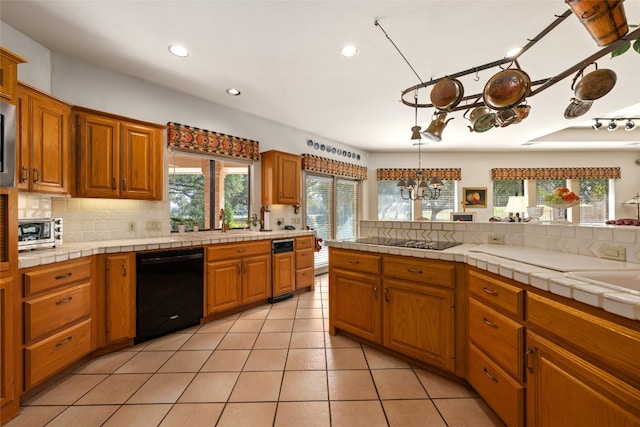 kitchen featuring tile countertops, a chandelier, hanging light fixtures, and black appliances