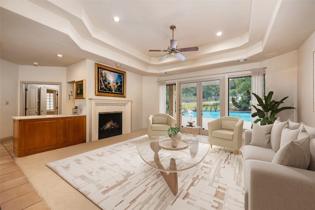 living room with ceiling fan and a tray ceiling