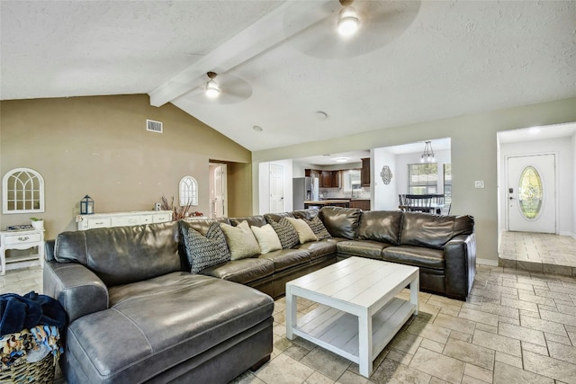 living room with vaulted ceiling with beams, ceiling fan, and a textured ceiling