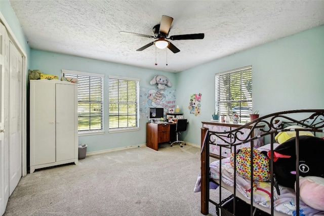 bedroom with light carpet, a textured ceiling, multiple windows, and ceiling fan