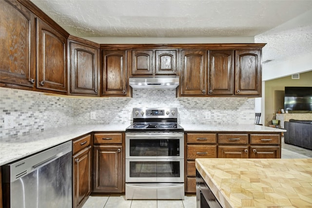 kitchen with appliances with stainless steel finishes, a textured ceiling, tasteful backsplash, and light tile patterned flooring