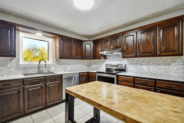 kitchen with sink, a textured ceiling, tasteful backsplash, dark brown cabinetry, and stainless steel appliances