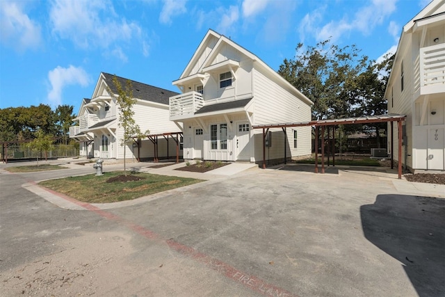 view of front of home with a carport, a balcony, and central AC unit