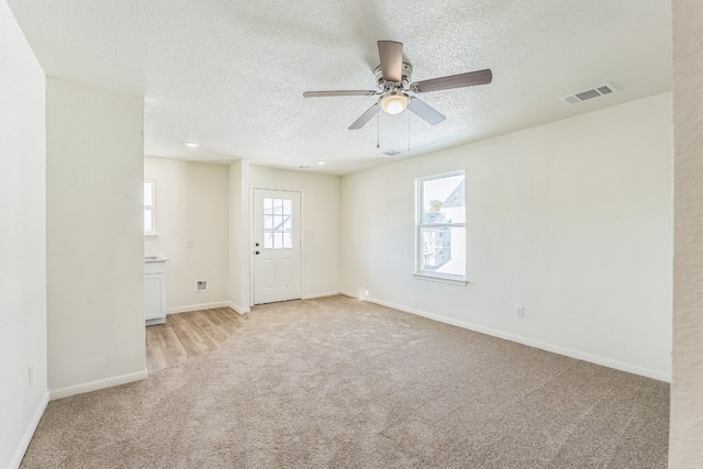 carpeted empty room featuring a textured ceiling and ceiling fan