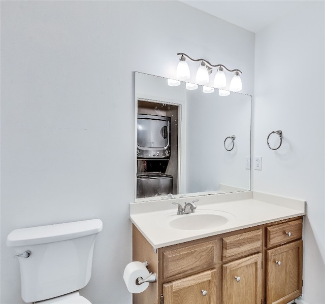 bathroom featuring vanity, toilet, and stacked washer / drying machine