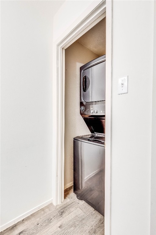 clothes washing area with light hardwood / wood-style floors and stacked washing maching and dryer