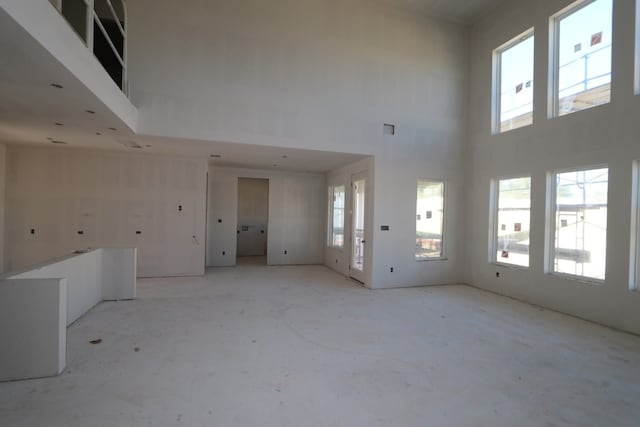 unfurnished living room featuring a towering ceiling