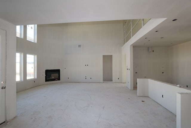 unfurnished living room with a fireplace and a towering ceiling