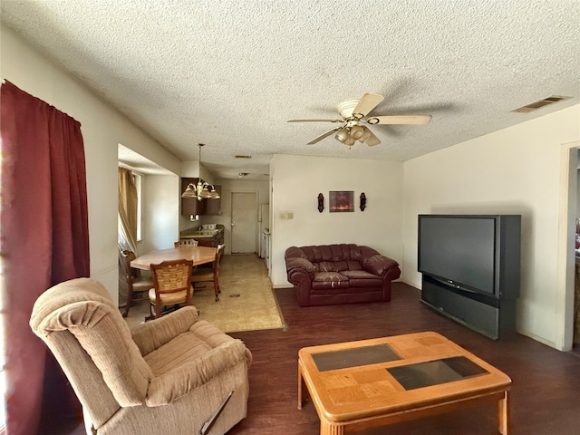 living room featuring a textured ceiling, ceiling fan with notable chandelier, and dark hardwood / wood-style floors