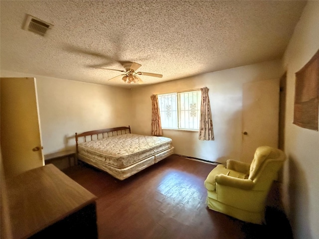 bedroom with ceiling fan, dark hardwood / wood-style flooring, and a textured ceiling