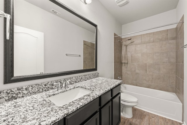 full bathroom featuring toilet, hardwood / wood-style floors, vanity, and tiled shower / bath