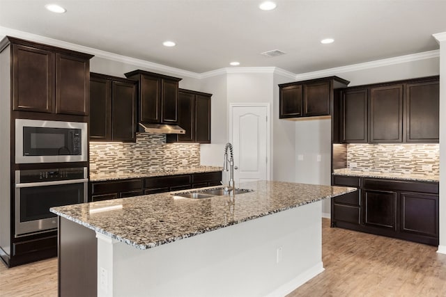 kitchen featuring sink, light hardwood / wood-style flooring, ornamental molding, an island with sink, and appliances with stainless steel finishes