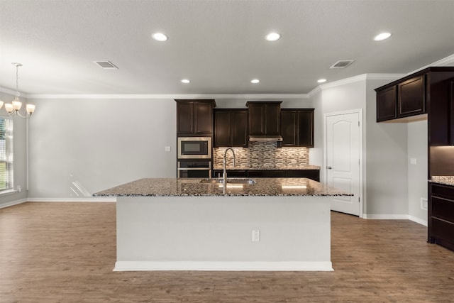 kitchen featuring dark brown cabinetry, sink, stainless steel appliances, and a center island with sink