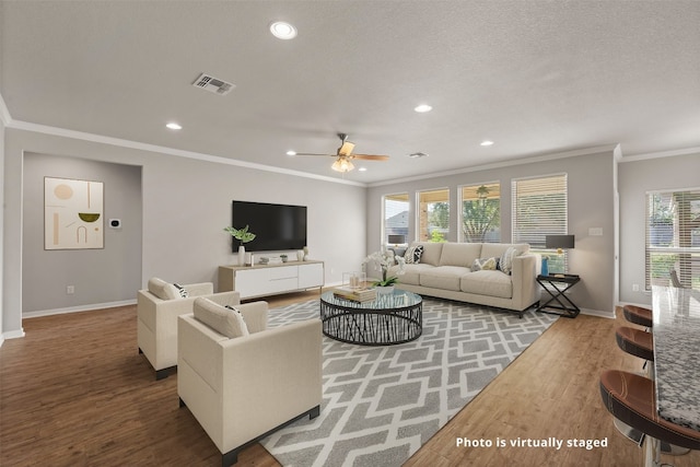 living room with a healthy amount of sunlight, ceiling fan, wood-type flooring, and ornamental molding