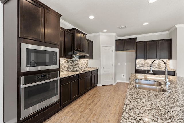 kitchen with light stone countertops, appliances with stainless steel finishes, light wood-type flooring, backsplash, and sink