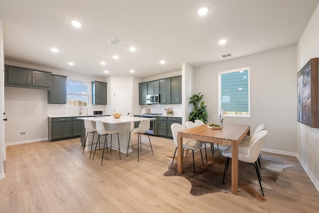 dining space with a wealth of natural light, sink, and light wood-type flooring