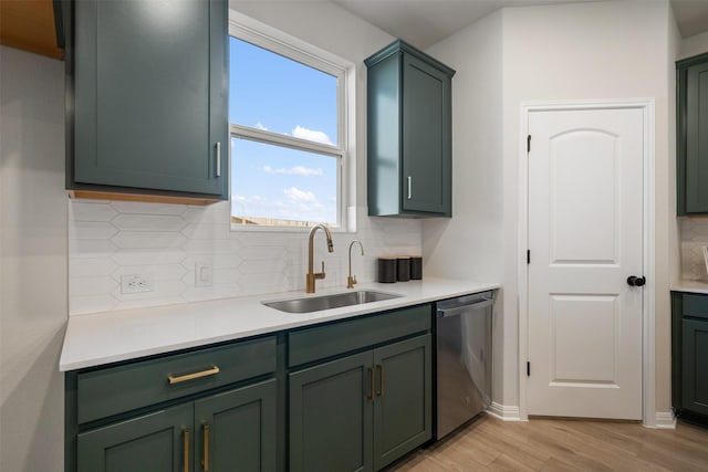 kitchen featuring sink, green cabinetry, stainless steel dishwasher, decorative backsplash, and light hardwood / wood-style flooring