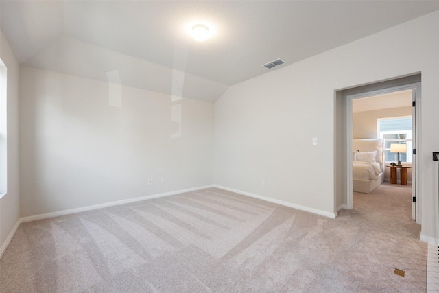 empty room featuring light colored carpet and lofted ceiling