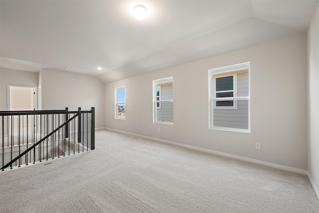 carpeted empty room with vaulted ceiling