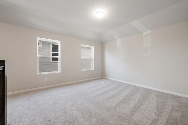 unfurnished room with light carpet and vaulted ceiling