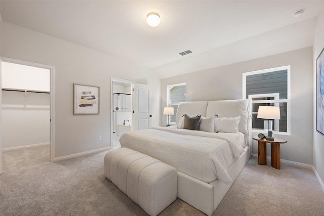 bedroom featuring connected bathroom, light colored carpet, a spacious closet, and a closet