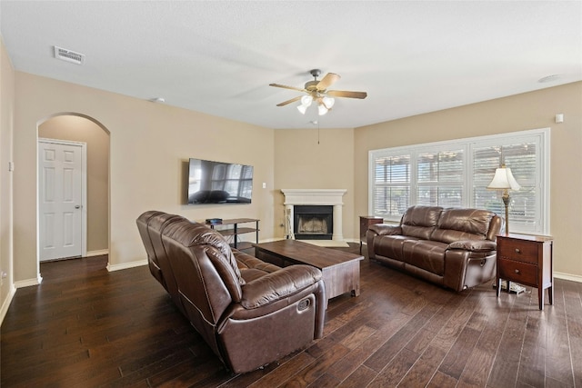 2603 White Stallion Way, Leander, TX 78641 - living room featuring arched walkways, a ceiling fan, dark wood finished floors, and a fireplace