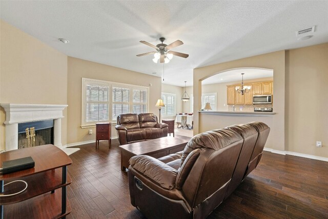 living room with a textured ceiling, ceiling fan with notable chandelier, and dark hardwood / wood-style floors