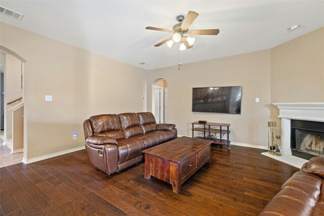 2603 White Stallion Way, Leander, TX 78641 - living area with arched walkways, a ceiling fan, wood finished floors, and a fireplace with raised hearth