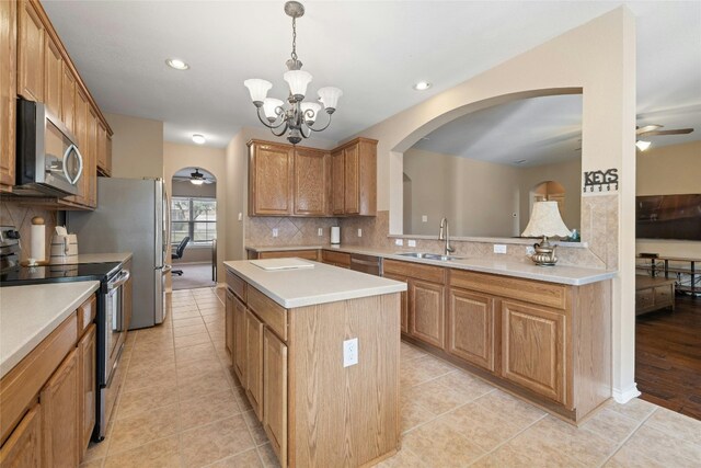 kitchen featuring stainless steel appliances, sink, a chandelier, a kitchen island, and hanging light fixtures