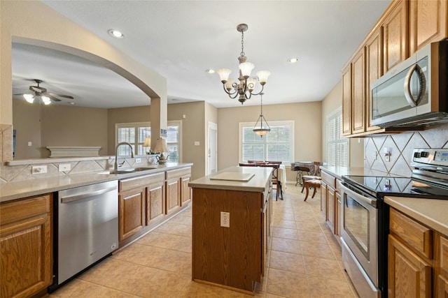 kitchen featuring sink, decorative backsplash, decorative light fixtures, a kitchen island, and stainless steel appliances