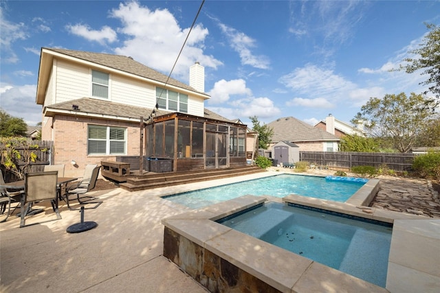 view of swimming pool featuring a sunroom, a storage shed, an in ground hot tub, and a wooden deck