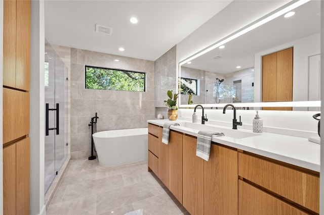 bathroom featuring plus walk in shower, vanity, tile patterned floors, and tile walls